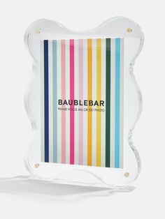 the baublebar logo is displayed on a striped glass plaque with gold trim