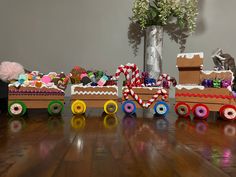 a wooden toy train sitting on top of a hard wood floor next to a vase filled with flowers