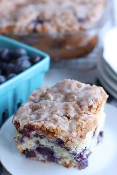 a piece of blueberry crumb cake on a plate next to a bowl of berries