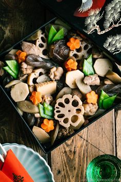 a box filled with different types of food on top of a wooden table next to an orange napkin