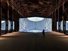 a person is standing in an empty room with large screens on the wall behind them