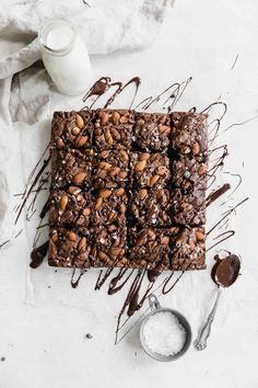 chocolate brownies with nuts on top and drizzled in chocolate sauce next to it