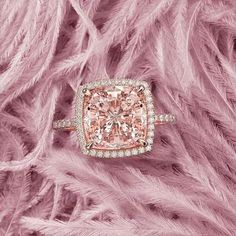 a pink diamond ring with diamonds on it and feathers in the background, all around