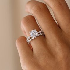 a woman's hand with a diamond ring on top of her finger and an engagement band