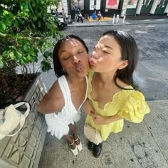 two women sitting on a bench kissing each other with their mouths open and tongue out