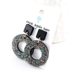 the earrings are decorated with multicolored sprinkles and black acrylic