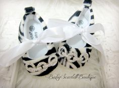 the baby shoes are decorated with zebra print and white ribbon, along with a bow