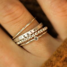 These rings are handmade in our Indiana studio. Each engraved ring starts from a spool of wire. They are handcut, handformed and soldered in the first process of creating your ring. They are then hammered to size, engraved, handbrushed, and polished. Each ring will have a small solder spot in the back because they are handmade, not machine made. We use yellow gold solder on our yellow and rose gold filled rings because rose gold solder contains carcinogens. The rings are very unique. There may b Mom Rings, Name Rings Silver, Personalized Stackable Rings, Birthstone Band, Jewelry Name, Stackable Rings Silver, Mom Ring, Name Ring, Beaded Ring