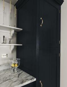 a kitchen with black cabinets and marble counter tops, gold handles on the door knobs