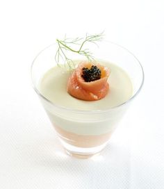 a small glass bowl filled with food on top of a white tableclothed surface