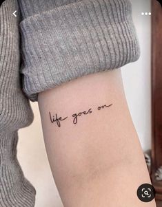 a woman's arm with the words life goes on written in cursive font