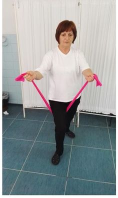 a woman is holding two pink ribbons in her hands while standing on a blue tile floor