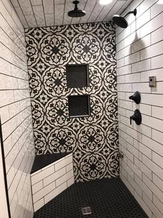 a bathroom with black and white tile on the walls, shower head, and hand held faucet