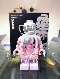 a pink and white lego figure sitting on top of a glass table