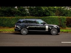 a black car parked in front of a hedge