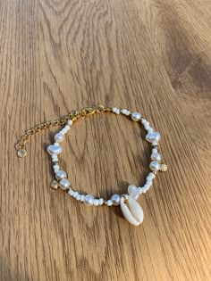 Dive into the beauty of the sea with our stunning Gold Beachy Shell Bracelet, a true treasure for those who adore the beach aesthetic. Crafted with delicate gold-toned metal, this bracelet perfectly captures the essence of a seaside escape. Each intricate shell charm reminiscent of sandy shores and ocean breeze, elegantly complemented by a lustrous pearl accent. The bracelet exudes a sense of natural beauty and coastal allure, making it a must-have accessory for beach lovers. Whether you're stro Sea Shell Bracelet Aesthetic, Sea Shell Bracelets, Shell Charm Bracelet, Coastal Bracelet Ideas, Shell Bracelet Aesthetic, Sea Shell Bracelet Diy, Sea Shell Jewelry Aesthetic, Aesthetic Handmade Jewelry, Beach Bracelets Aesthetic