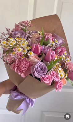 a person holding a bouquet of flowers in their hand with the door open behind them