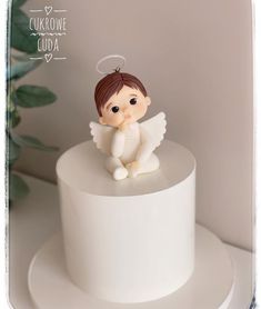 a small angel figurine sitting on top of a white cake