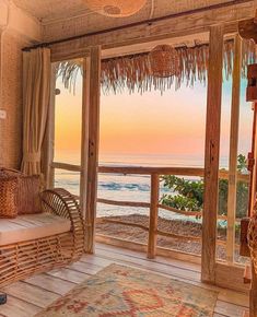 a living room with a view of the ocean and sunset from it's balcony