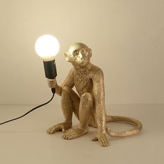 a monkey lamp sitting on top of a table with a light bulb in it's mouth