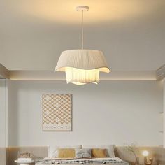 a bed sitting under a light next to a lamp in a room with white walls