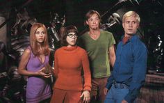 four people standing next to each other in front of an alien creature with their hands on their hips