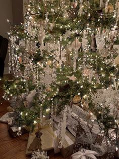 a christmas tree is decorated with silver and white ornaments, bows, and other holiday decorations