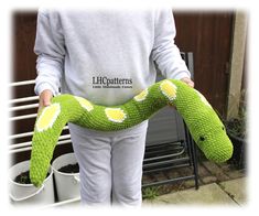 a woman holding a green snake in her hands and wearing a white shirt with yellow dots on it