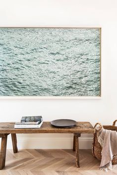 a wooden table sitting in front of a wall with a painting hanging on it's side