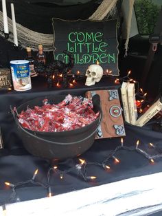 a table topped with a bowl of candy next to a sign that says come little halloween