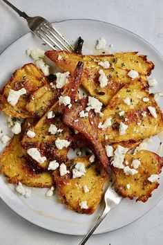 a white plate topped with potato wedges covered in feta cheese and parsley