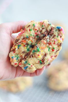 a hand holding up a cookie with sprinkles