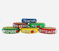 six colorful bracelets with the words teach and an apple on each one, all in different colors