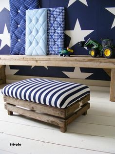 a bench made out of pallets with stars painted on the wall behind it and a toy tractor