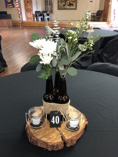 two vases with flowers in them are on a wood slice that is sitting on a table