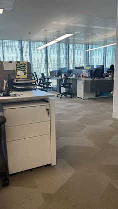 an office with cubicles, desks and chairs in the middle of the room