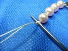 a pair of scissors and some pearls on a piece of blue material with white thread