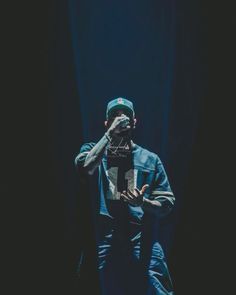 a man sitting in front of a black background with his hands on his face and one hand up to his mouth