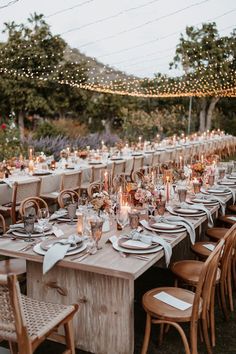 an outdoor dinner table set up with candles and place settings