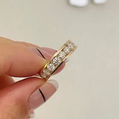 a hand holding a gold ring with three diamonds on it's sides and the middle finger