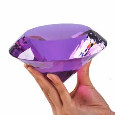 a purple diamond being held in front of a white background