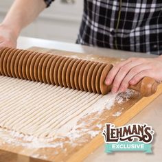 a person rolling dough on top of a wooden board