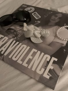 a magazine with sunglasses on top of it next to a pair of pearls and a necklace