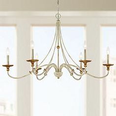 a white chandelier hanging from a ceiling in a room with windows and chairs