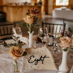 the table is set with white linens and floral centerpieces in vases