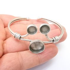 a hand holding a silver bracelet with two circles on it