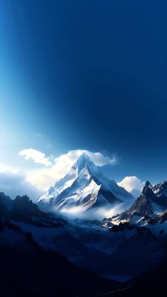 the mountains are covered in clouds and blue hues as they rise into the sky