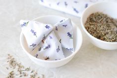 two bowls filled with different types of herbs and one has a napkin on top of it