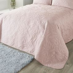 a bed with pink comforter and pillows on it