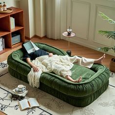 a person laying on a green couch with a laptop